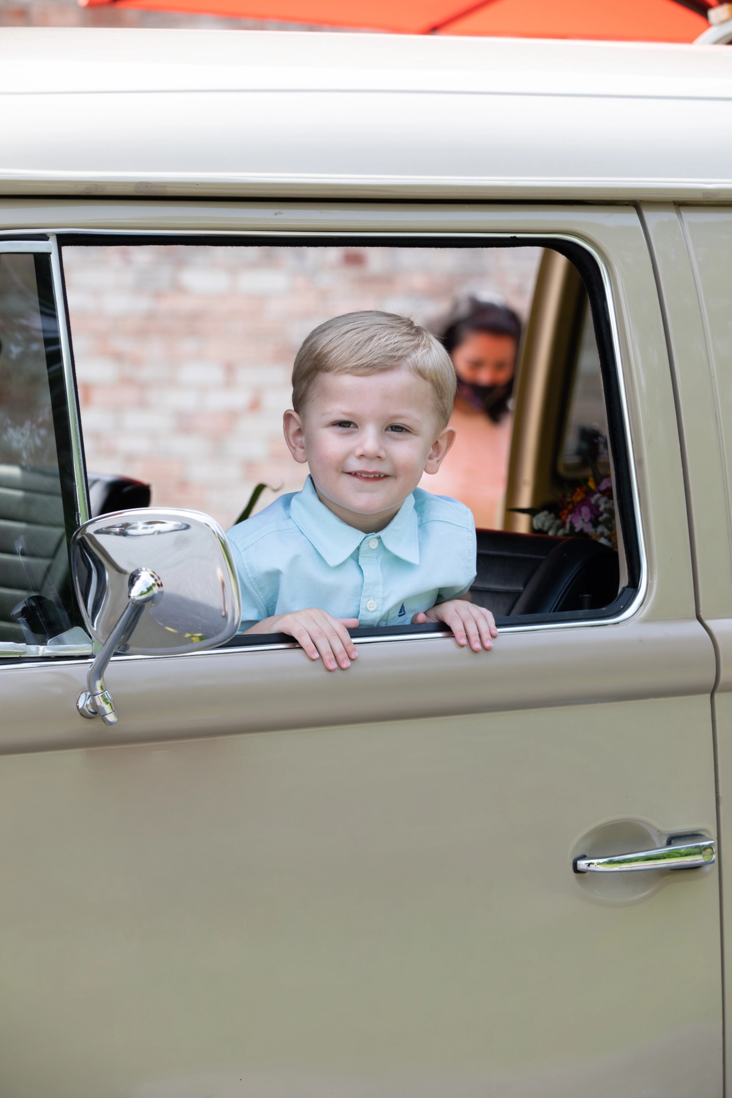 A young guest smiling from the flower-filled window of the VW Blooming Bus